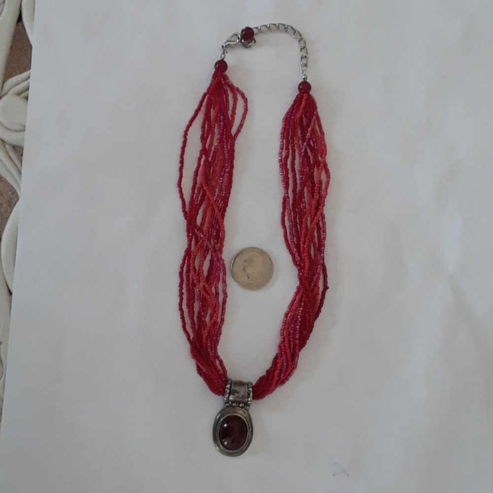 Red seed bead necklace with silver tone pendant.